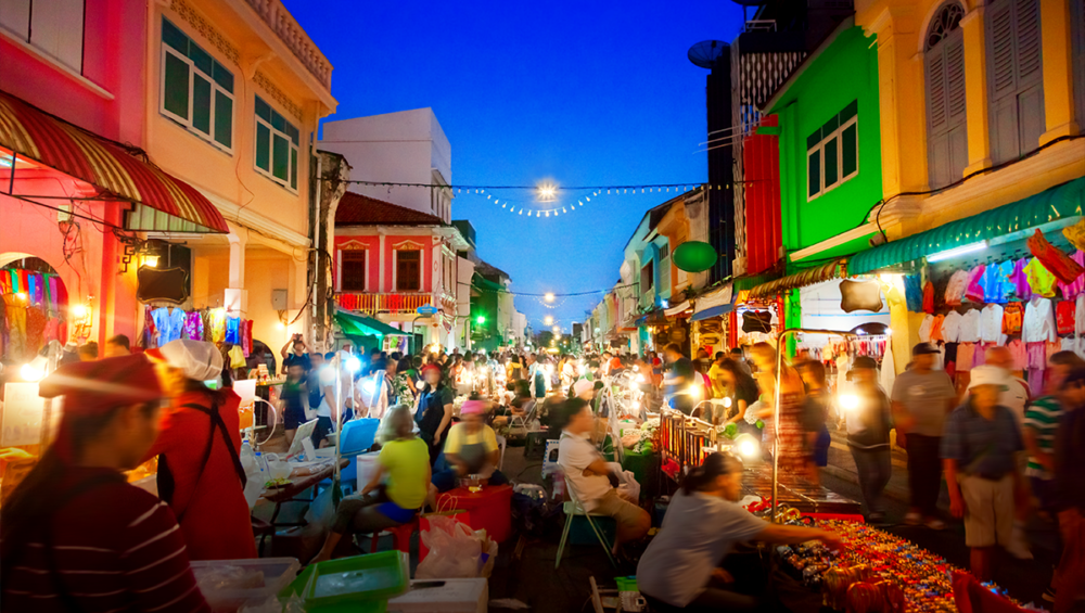 A bustling night market in Phuket showcasing vibrant stalls filled with local crafts and handmade souvenirs.