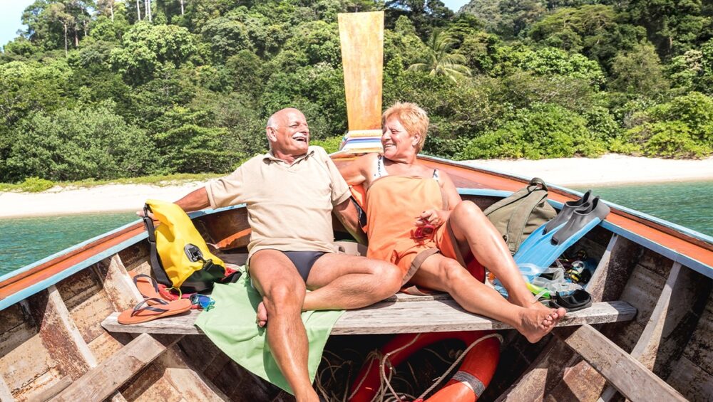 Senior couple enjoying a sunset view on a boat in Phuket, Thailand, with the Andaman Sea's golden hour colors.