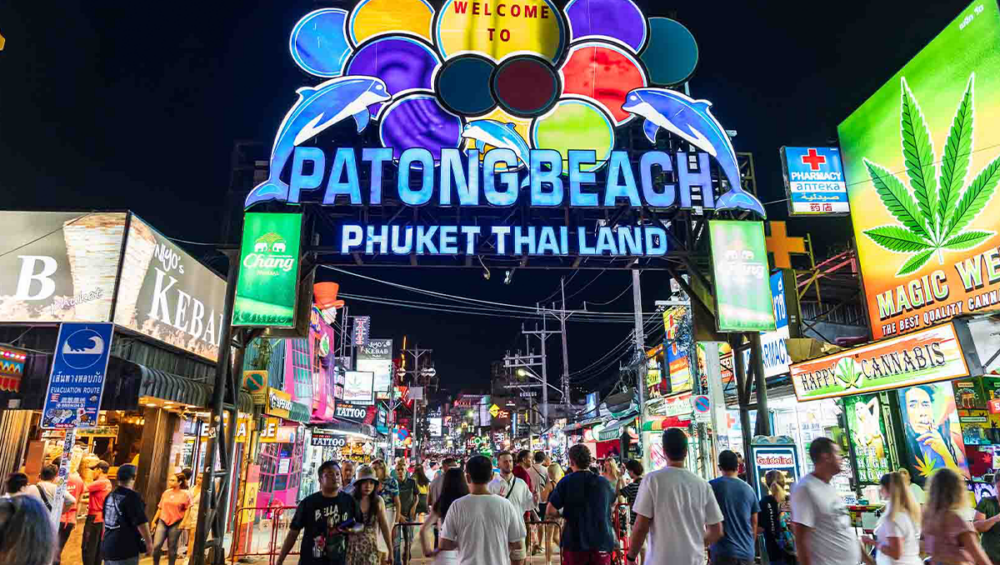 Vibrant nightlife in Phuket featuring neon lights on Bangla Road, crowded with tourists and locals enjoying the bustling atmosphere.